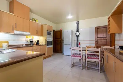 a kitchen with wooden cabinets and a table and chairs at TAC - Vila Tina Vilamoura in Quarteira