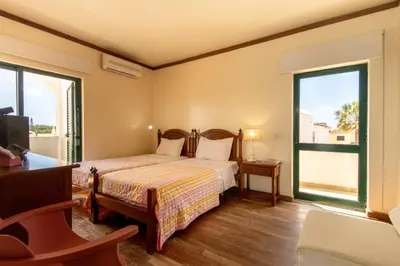 a bedroom with a bed and two large windows at TAC - Vila Tina Vilamoura in Quarteira