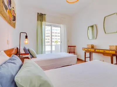 a hotel room with two beds and a desk at AL - Apartamento Maré Baixa in Quarteira