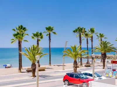 a red car parked next to a beach with palm trees at AL - Apartamento Maré Baixa in Quarteira