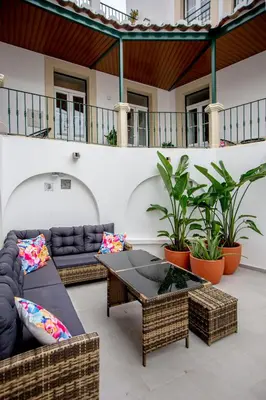 a patio with couches and tables and plants at Guest House Jacarandá Faro in Faro