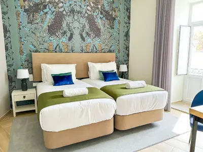 a bedroom with two beds with blue pillows at Guest House Jacarandá Faro in Faro