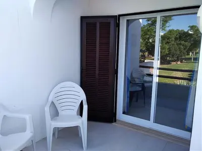 a white chair sitting on a porch with a sliding glass door at The Sun - Clube Albufeira Garden Village in Albufeira