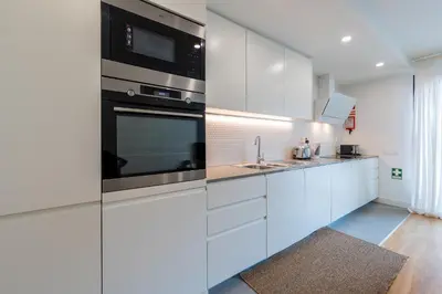 a white kitchen with a sink and a microwave at Compromisso 25 in Faro