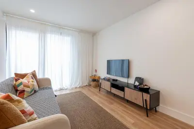 a living room with a couch and a flat screen tv at Compromisso 25 in Faro