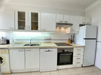 a kitchen with white cabinets and a sink and a refrigerator at Vilamoura Twins 1 With Pool by Homing in Vilamoura