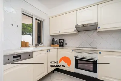 a kitchen with white cabinets and an orange home hollidays sign at #174 T2 em Zona Tranquila by Home Holidays in Albufeira