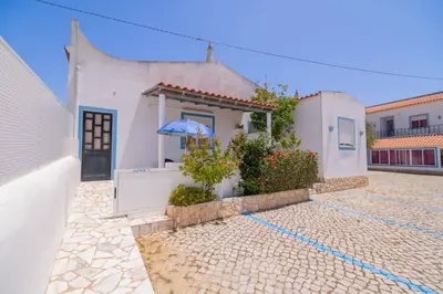 a white house with a blue umbrella in a courtyard at Casinha VII by Innkeeper in Guia
