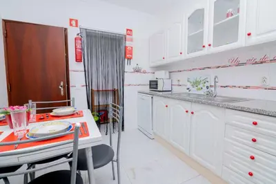 a kitchen with white cabinets and a table and a counter at Casinha VII by Innkeeper in Guia