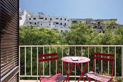 two red chairs and a pink table on a balcony at Hanna's Sunny Apartment in Albufeira