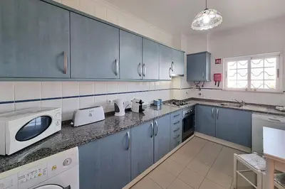 a kitchen with blue cabinets and a white microwave at Sea Beside in Albufeira