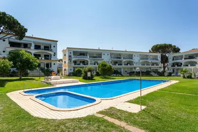an image of a swimming pool in front of a building at Host Wise - Amazing Sunny Flat - Swimming Pool & Terrace in Vilamoura
