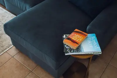 a book sitting on a table next to a blue couch at CASA AMOR JACARANDA - Ocean View Modern Vila in Albufeira
