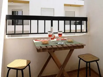 a table with two chairs and two glasses of wine at Mar á vista by FHR 2 minutos á praia in Quarteira