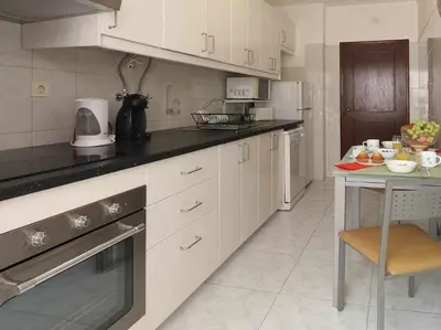 a kitchen with white cabinets and a table in it at Mar á vista by FHR 2 minutos á praia in Quarteira