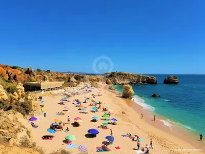 a group of people on a beach with umbrellas at Studio Camélia 67 at São Rafael Beach - Albufeira in Albufeira