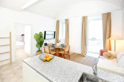 a kitchen and living room with a table and a couch at Doce Faro Niente Apartment in Faro