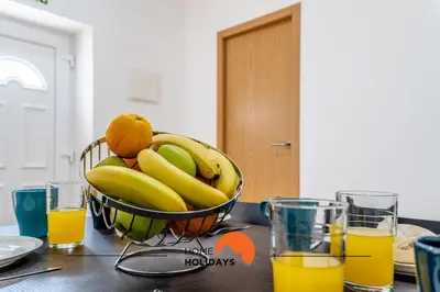 a bowl of bananas and oranges on a table with glasses of orange juice at #178 Monte das Churras 1 by Home Holidays in Albufeira
