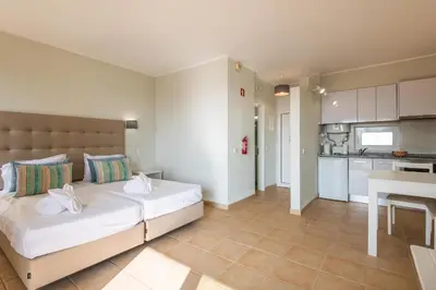 a bedroom with a large bed and a kitchen at Albufeira Jardim Studio with Sea View - Free Wi-Fi - Pool in Albufeira