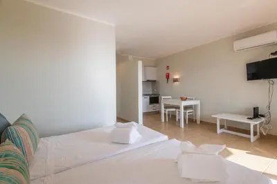 a bedroom with a white bed and a kitchen at Albufeira Jardim Studio with Sea View - Free Wi-Fi - Pool in Albufeira