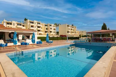 a swimming pool with chairs and umbrellas and buildings at Albufeira Jardim Studio with Sea View - Free Wi-Fi - Pool in Albufeira