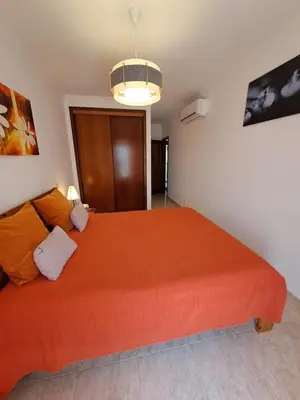 a bedroom with two beds and a couch and a chandelier at T2 Vila Atlântida Praia Vilamoura in Quarteira