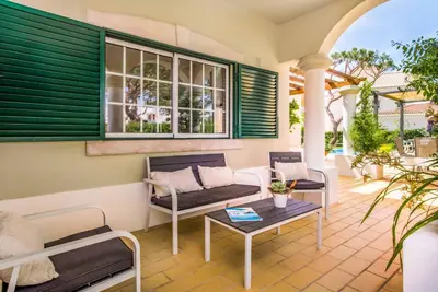 a porch with a couch and chairs and a table at Villa Vargues in Quarteira
