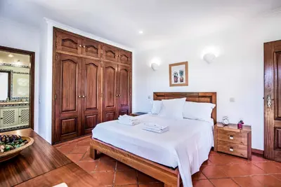 a bedroom with a large white bed with wooden cabinets at Villa Vargues in Quarteira