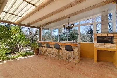 an outdoor kitchen with a bar with stools at Casa Palma in Paderne