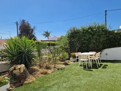 a garden with a table and chairs on the grass at Airy 3br, AC, Garden, 2min Strip, 8min Oura Beach in Albufeira