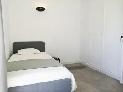 a bedroom with a bed with white walls at Airy 3br, AC, Garden, 2min Strip, 8min Oura Beach in Albufeira