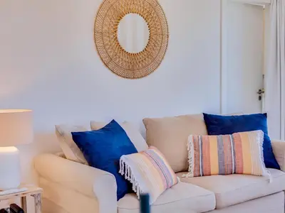 a white couch with blue pillows and a mirror at AL - Vilamoura Algardia in Vilamoura