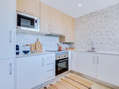 a white kitchen with white cabinets and a microwave at AL - Vilamoura Algardia in Vilamoura