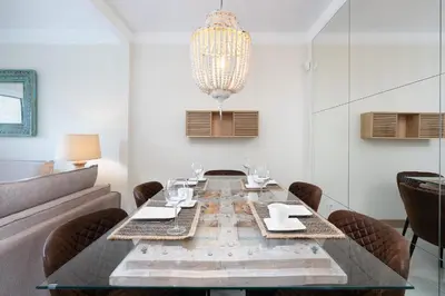 a white bedroom with a bed and a chandelier at Apartament Belharucas, 400 meters from beach in Albufeira