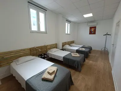 a room with three beds and two tables in it at Albergaria Formosa in Faro