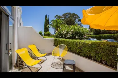a group of chairs and an umbrella on a balcony at Ocean Oasis by LovelyStay in Albufeira