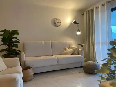 a living room with a white couch and a clock on the wall at Solar Dos Pinheiros in Quarteira