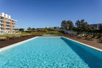a large swimming pool with chairs and a building at The Albufeira Concierge - Prime Lounge Design in Albufeira
