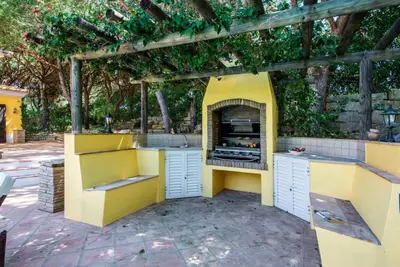 an outdoor kitchen with a pizza oven under a pergola at Villa Plaza - beautiful spacious house off roundabout 6 Quinta Do Lago in Quinta do Lago