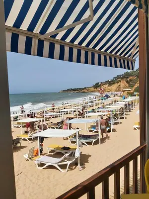 a beach with many chairs and tables and the ocean at Albufeira - Casa Balaia Resort in Albufeira