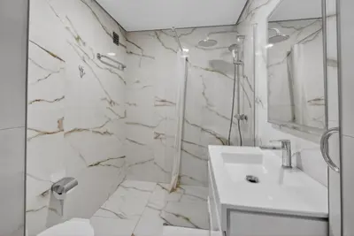 a bathroom with a white sink and a marble wall at Estudio Balaia by Villas Key in Albufeira