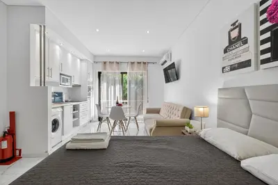 a white living room with a bed and a kitchen at Estudio Balaia by Villas Key in Albufeira