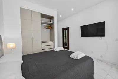 a white bedroom with a bed and a flat screen tv at Estudio Balaia by Villas Key in Albufeira