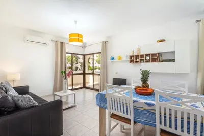a living room with a table and a couch at Host Wise - Fresh Sunny Flat with Pool & Terrace in Olhos de Água
