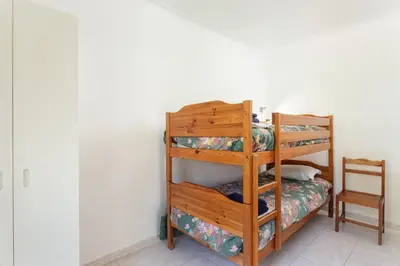 a bedroom with a bunk bed with a wooden bunk ladder at Host Wise - Fresh Sunny Flat with Pool & Terrace in Olhos de Água