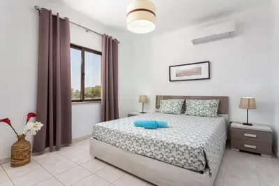 a white bedroom with a bed and a window at Host Wise - Fresh Sunny Flat with Pool & Terrace in Olhos de Água