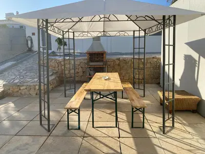 a table and bench under a tent on a patio at Moradia Olival- BBQ, 2 Quartos, Quintal in Albufeira