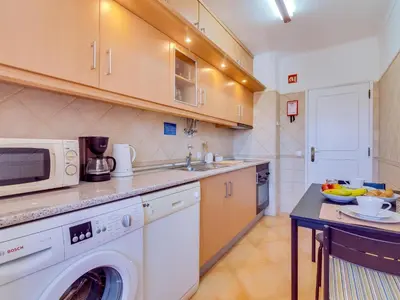 a kitchen with a washing machine and a microwave at AL - Apartamento Quinta do Romão in Quarteira