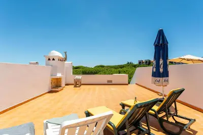 a patio with chairs and an umbrella on a roof at Pine Trees Penthouse in Olhos de Água