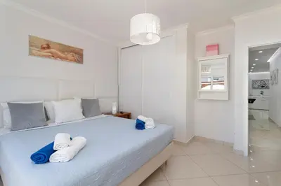 a white bedroom with a bed with towels on it at Zurrinha holidays whit jacuzzi in Quarteira